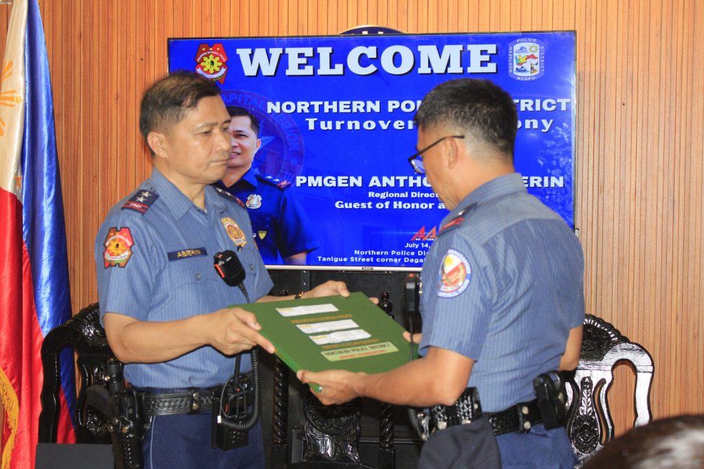 May be an image of 2 people and text that says 'POLICE WEL WELCOME NCRPO NORTHERN PO Turnover PN RICT ony ny PMGEN ANTHO Reglonal Direc Guest of Honor a S ADER ERIN July Tanigueseoe ש 14. Northern Di- Tanigue Street corner Daga .በንዶ።'